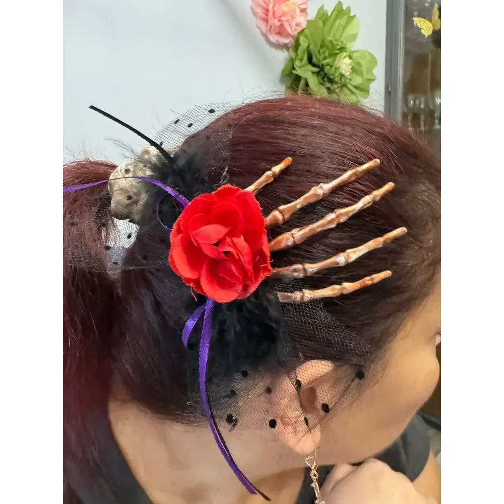 Purple rose hair clip with black netting and purple ribbon on a skeleton hand